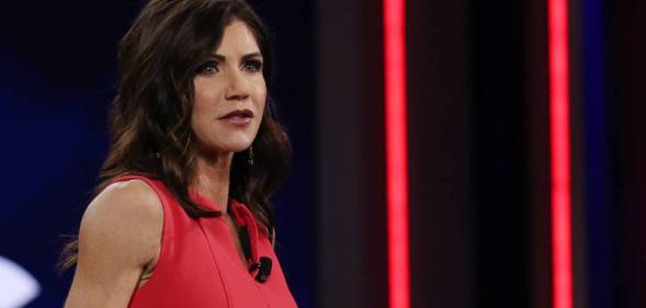 South Dakota governor Kristi Noem wears a red outfits as she stands at a podium