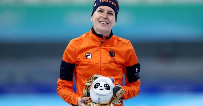 Ireen Wüst, an Olympic speed skater, poses with a panda mascot for the Beijing Olympics while wearing an orange jacket