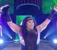 Nyla Rose, a wrestler, holds up a championship belt above her head after a victory in the ring