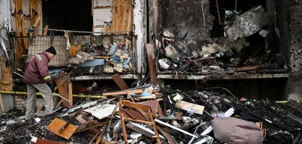 A man clears debris at a damaged residential building at Koshytsa Street, a suburb of the Ukrainian capital Kyiv, where a military shell allegedly hit, on February 25, 2022.