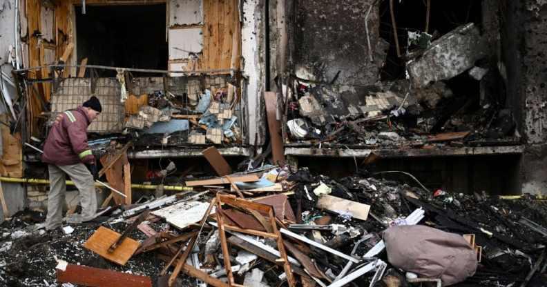 A man clears debris at a damaged residential building at Koshytsa Street, a suburb of the Ukrainian capital Kyiv, where a military shell allegedly hit, on February 25, 2022.