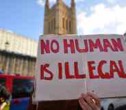 A protester holds a placard saying No Human Is Illegal