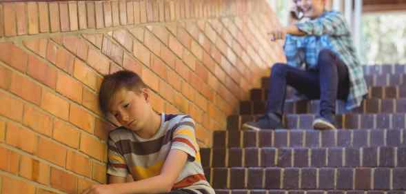 School friend bullying a sad boy in school corridor at school