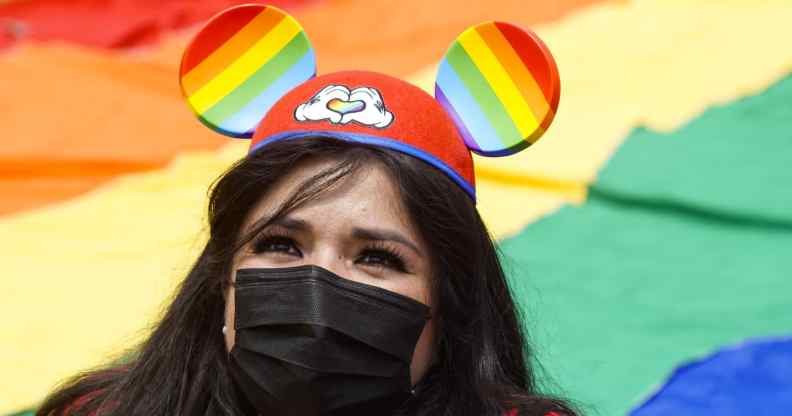 A woman wears Mickey Mouse ears with the Pride colours