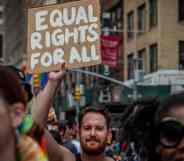 A participant is seen holding a sign reading "Equal rights for all" at a LGBT+ march