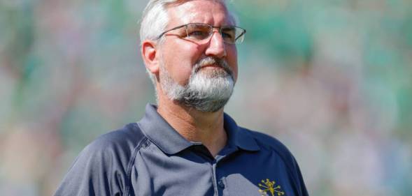 Eric Holcomb, the governor of Indiana, wears a blue polo shirt with a gold logo over his left chest