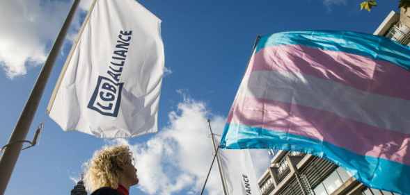 An activist holds a transgender pride flag at a protest by Transgender Action Block and supporters outside the first annual conference of the LGB Alliance at the Queen Elizabeth II Centre on 21st October 2021.