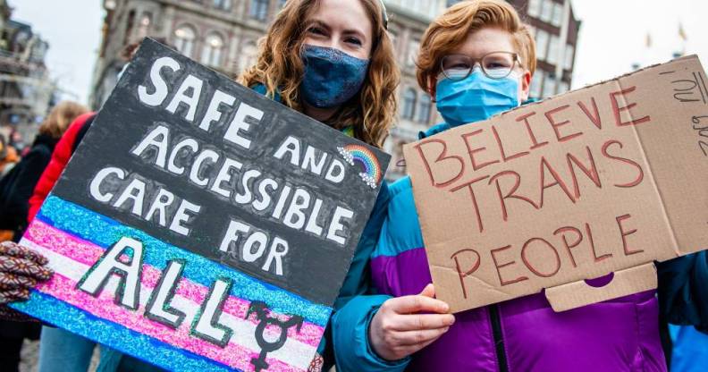 Two people hold placards in support of trans people