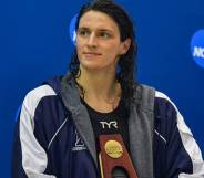 University of Pennsylvania swimmer Lia Thomas holds an NCAA trophy while she looks off to the side