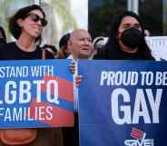 Two people hold signs reading "Stand with LGBTQ families" and "Proud to be gay" as they protest the passage of Florida's "Don't Say Gay" bill