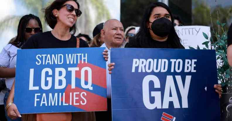 Two people hold signs reading "Stand with LGBTQ families" and "Proud to be gay" as they protest the passage of Florida's "Don't Say Gay" bill