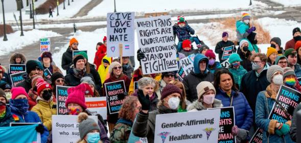 Crowd of people hold up signs in support of trans youth across the USA