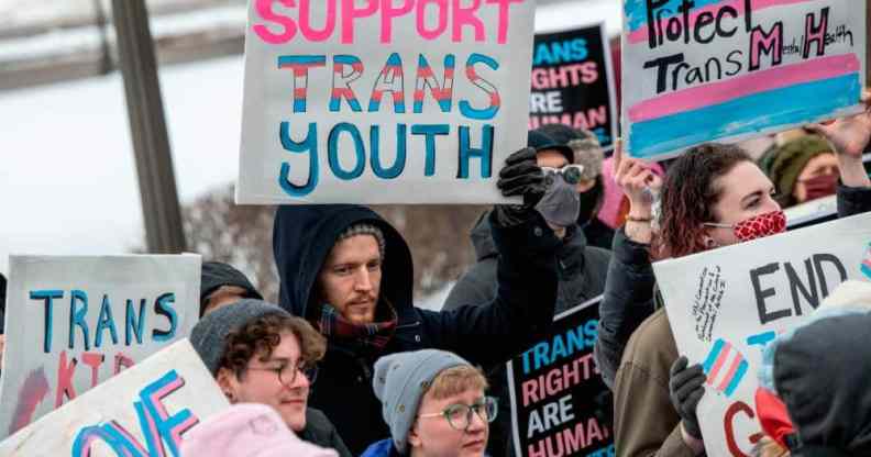 Person holds up a sign that reads "support trans youth" amid a rally in support of trans kids across the USA