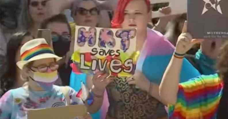 A person holds a sign up in support of the trans community that reads "HRT saves lives" amid protests in Texas