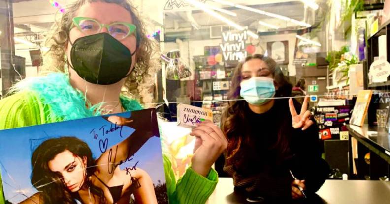 Charli XCX and fan Tabby Lamb pose with signed items including a vinyl copy of Charli's album CRASH and a packet of Lamb's oestrogen