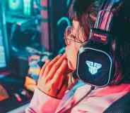 A person wearing gaming headphones looks down at their PC gaming set up