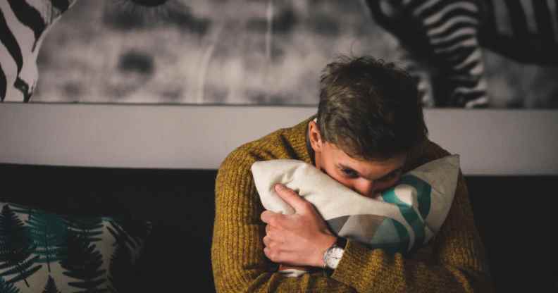 A man hugs a pillow in a bedroom