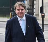 Conservative MP Jamie Wallis walks down the street wearing a white shirt, light blue tie and a suit jacket