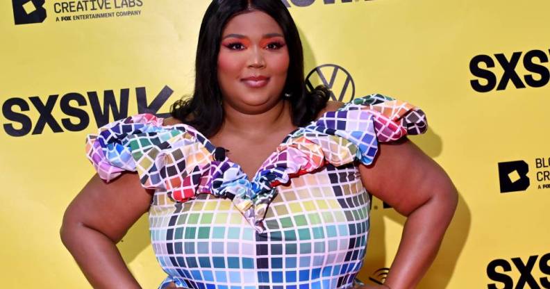 Lizzo wears a colourful, rainbow block outfit as she stands in front of a yellow background with the black SXSW logo on it