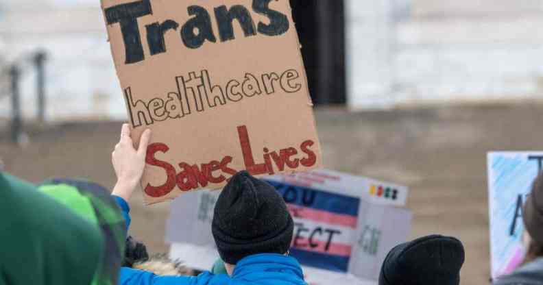 A person holds up a sign that reads "Trans healthcare saves lives" during a protest