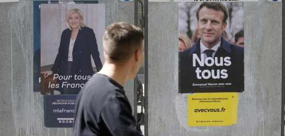 A man walks past official campaign posters of Marine Le Pen Emmanuel Macron