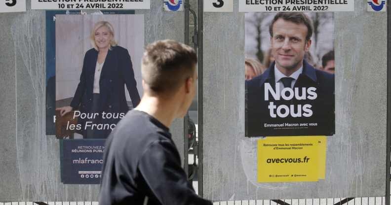 A man walks past official campaign posters of Marine Le Pen Emmanuel Macron