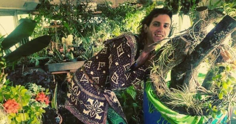 Fern Feather, a white trans woman, is seen surrounded by plants