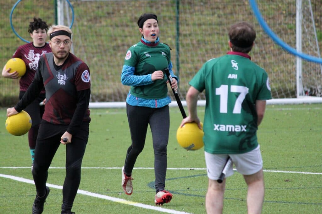 Four quidditch players running with yellow balls