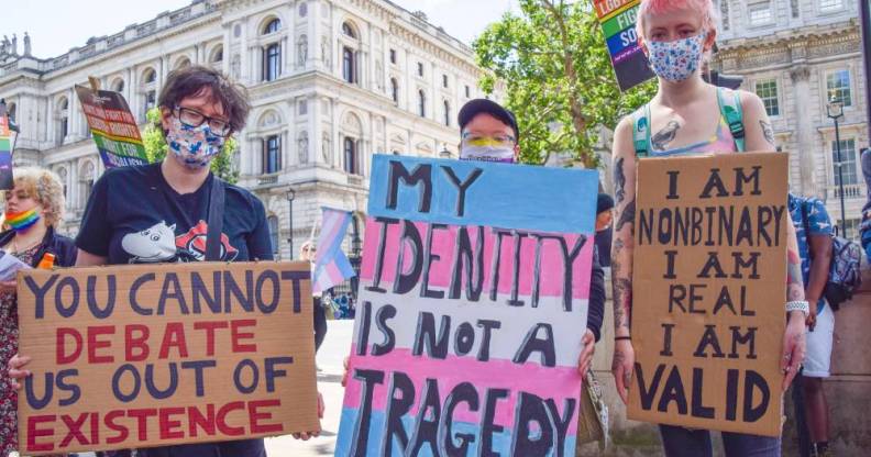 several people hold up signs during a trans rights protest one reads "you cannot debate us out of existence", "my identity is not a tragedy" and "I am non-binary, I am real, I am valid"