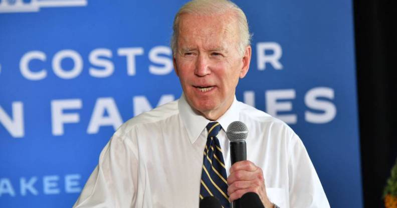 President Joe Biden speaks into a microphone while wearing a white button up shirt and a dark tie with stripes