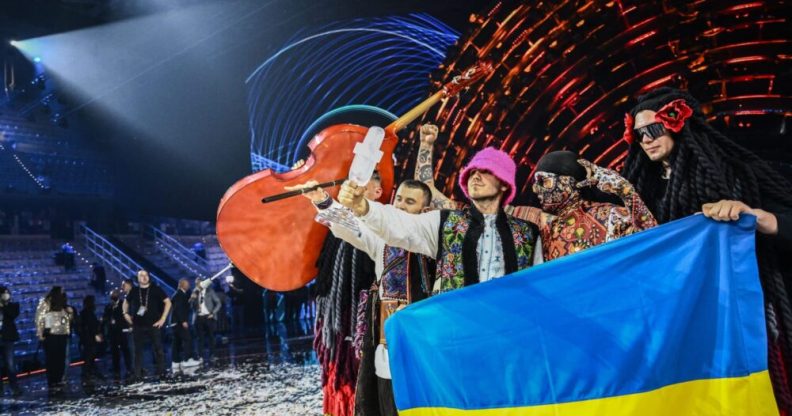 Ukraine's Kalush Orchestra hold the Eurovision trophy and a Ukraine flag