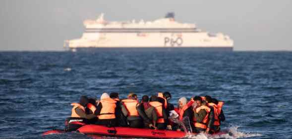 Migrants packed tightly onto a small inflatable boat bail water out as they attempt to cross the English Channel.