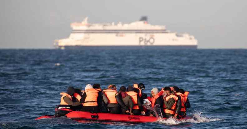 Migrants packed tightly onto a small inflatable boat bail water out as they attempt to cross the English Channel.