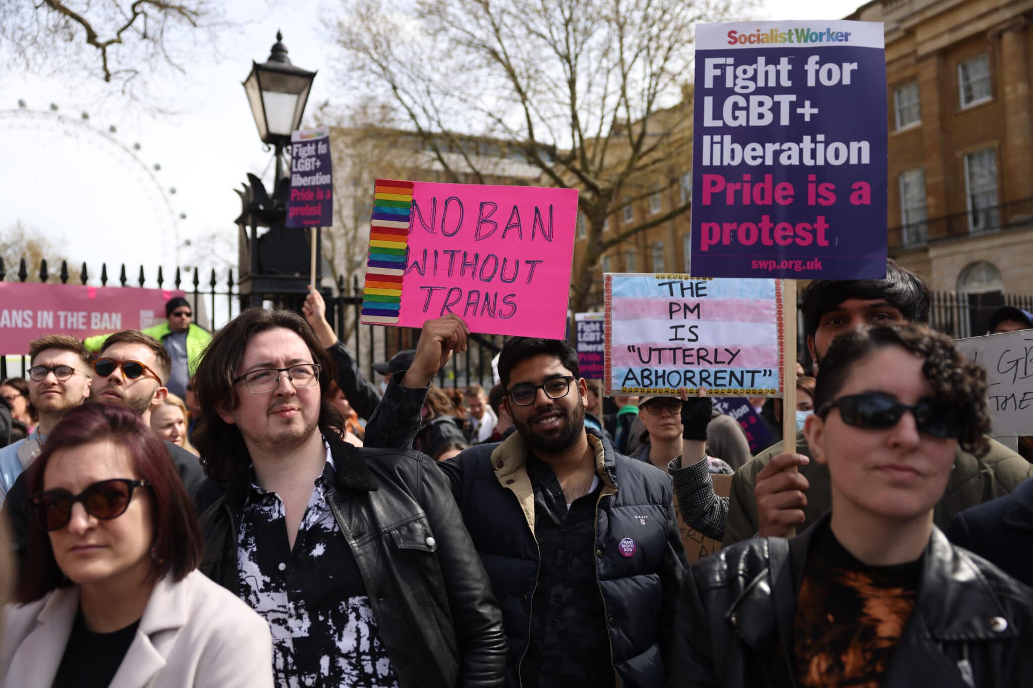 Demonstrators hold placards during the No Ban Without Trans protest