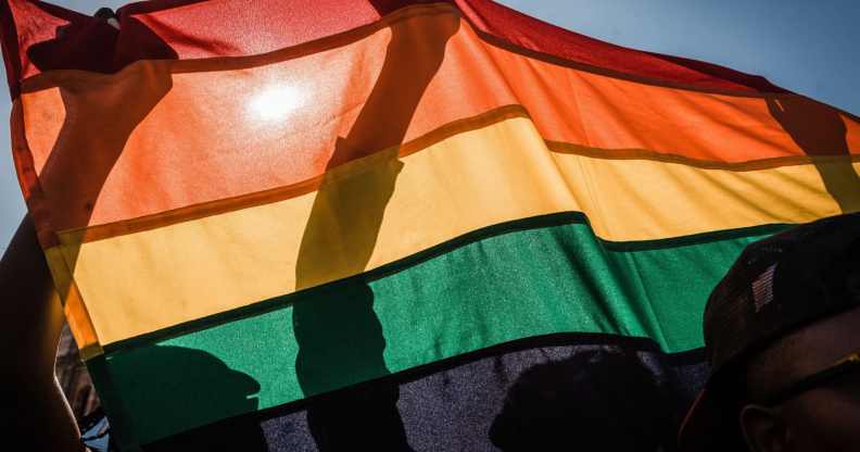 People hold up an LGBTQ+ Pride flag