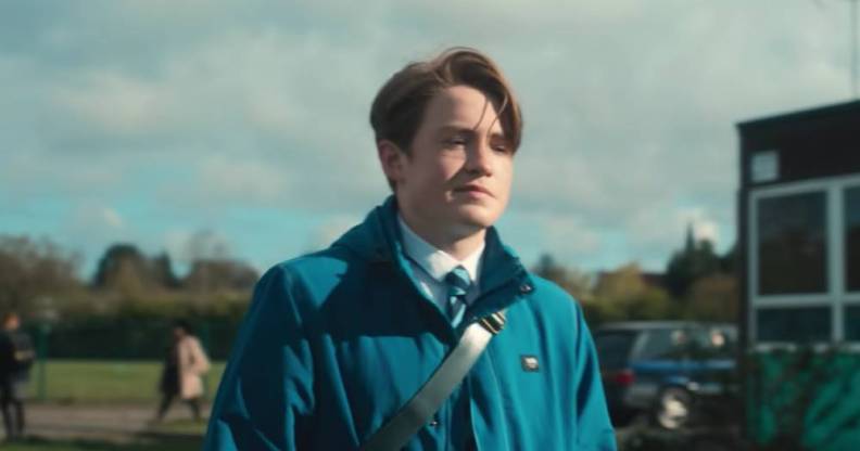 A still from Netflix's Heartstopper which shows Kit Connor as Nick Nelson wearing his school uniform and light blue coat
