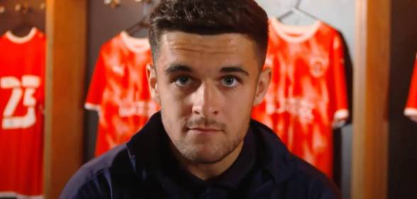 Blackpool football star Jake Daniels stares at the camera with football uniforms in the background