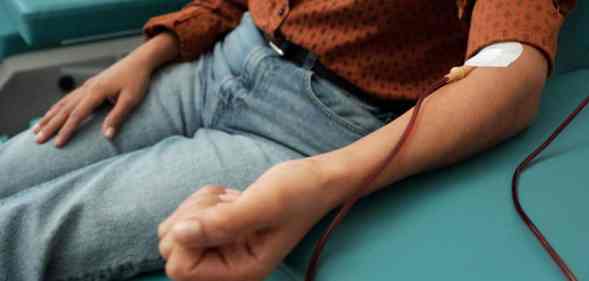 A person wearing a brown shirt with black polka dots and light blue jeans while donating blood