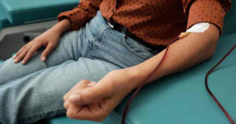 A person wearing a brown shirt with black polka dots and light blue jeans while donating blood