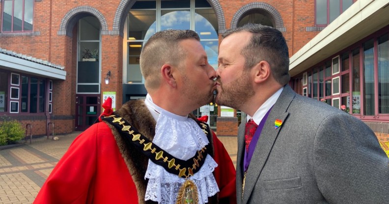 Richard Jones, in his red ceremonial mayor's cloak, kissing his partner, also named RIchard, who is wearing a grey suit