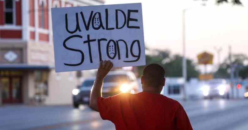 A person, with their back to the camera, holds a placard that says Uvalde strong