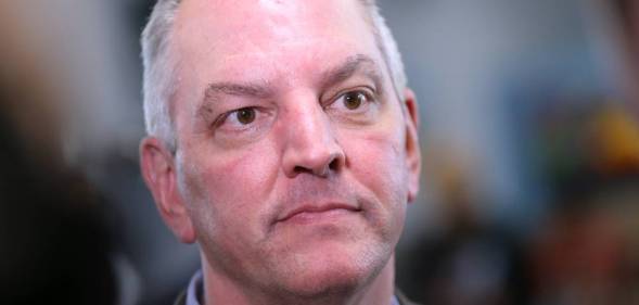 Louisiana governor John Bel Edwards stares slightly off camera while wearing a blue shirt and grey jacket