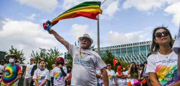 A person wearing a white shirt holds up a rainbow flag during a demonstration denouncing Florida's 'Don't Say Gay' law