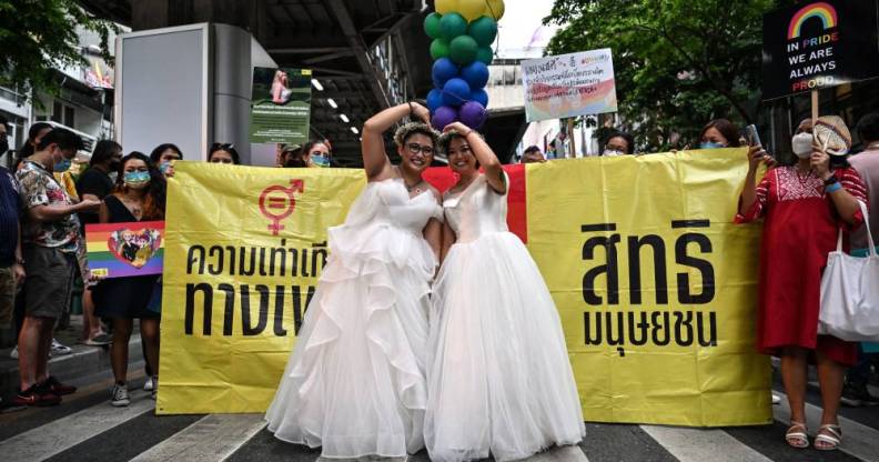 A same-sex couple poses in wedding dresses as members of the LGBTQIA+ community take part in the Pride March in Bangkok, Thailand