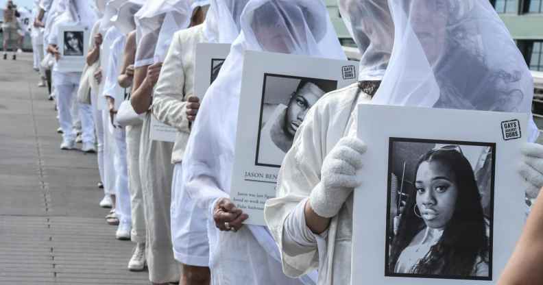 People wearing all white hold up signs of mass shooting victims, including Pulse