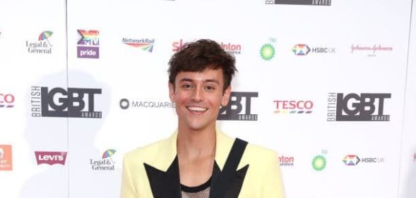 Tom Daley, dressed a pale yellow and black blazer, stands in front of the British LGBT Awards upon arrival