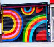 Dalston Superstore's exterior shutter, decorated in colourful rainbow display of colours. On either side are other small, lcoal London businesses.