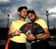 Two 2022 Mardi Gras volunteers pose together holding a fan, while wearing lemon yellow t-shirts.