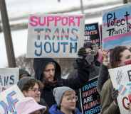 Families hold placards at a rally against increasing legislative attacks on trans kids across the US