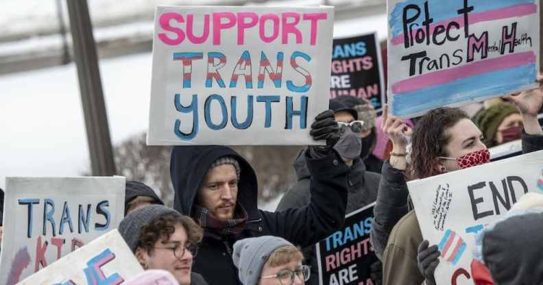 Families hold placards at a rally against increasing legislative attacks on trans kids across the US